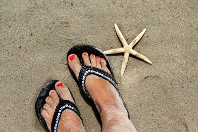 Beautiful female feet on the beach and starfish 