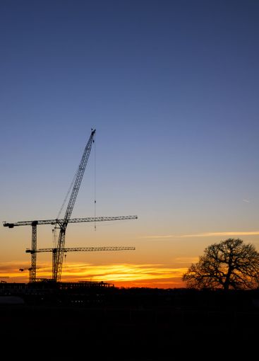 Silhouettes of construction cranes against the evening...