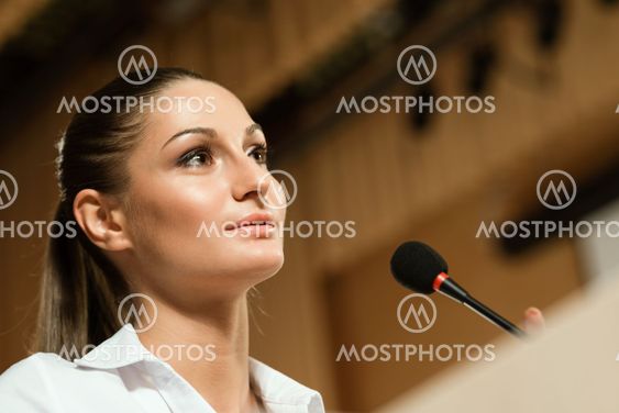 Business woman speaks into a microphone