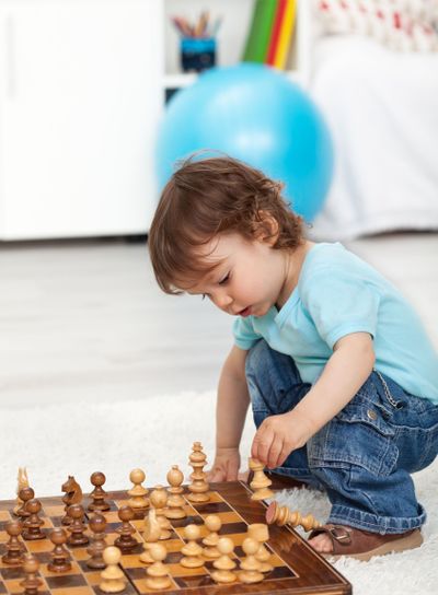 Toddler boy playing with chess pieces