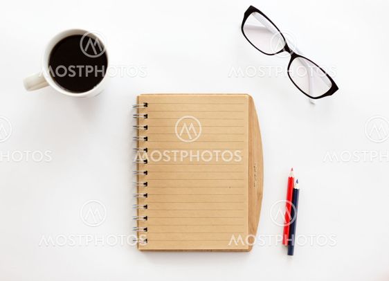 White office desk with a notebook and pencils, glasses