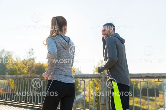 happy couple with earphones running outdoors