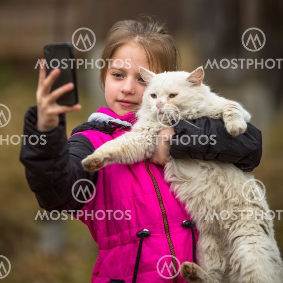 Little girl photographs herself with a stray cat on the...