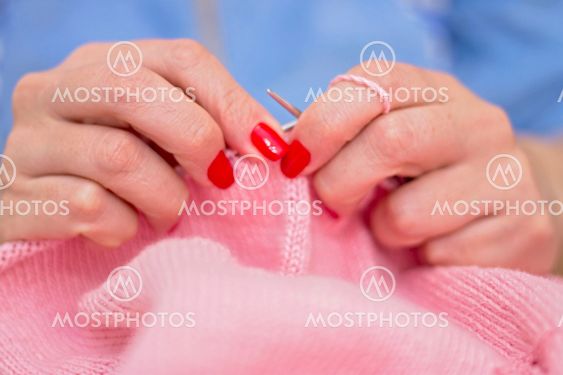 Woman knits with knitting needles pink sweater from...