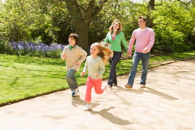 Family running on path holding hands smiling