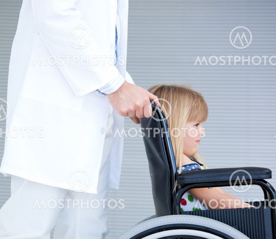 Smiling little girl sitting on the wheelchair supported by a doctor