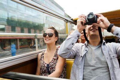 smiling couple with camera traveling by tour bus