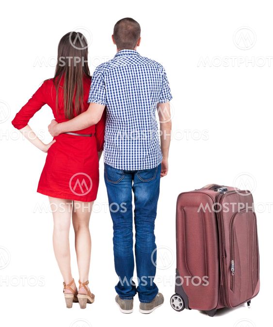 Back view of young couple traveling with suitcas .