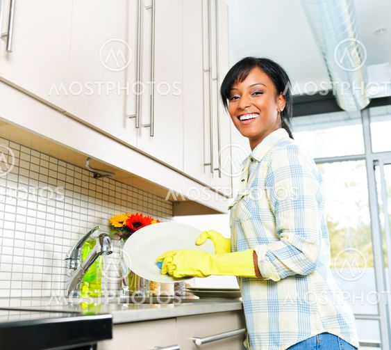 Happy young woman washing dishes