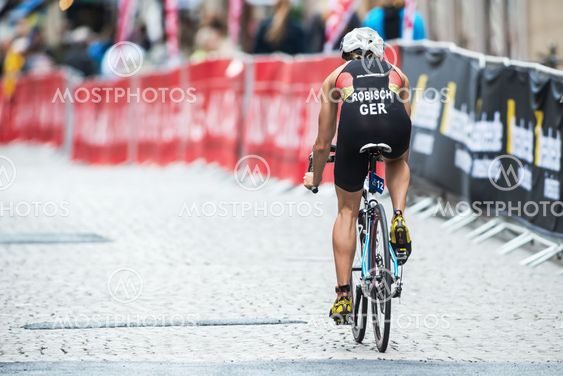 Back of Rebecca Robisch from Germany cycling in rain at...