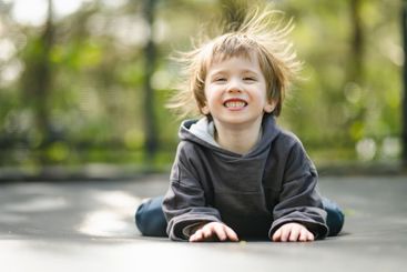Little boy jumping on a trampoline in a backyard on warm...