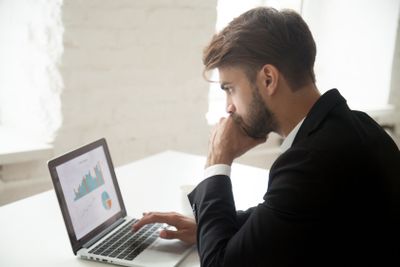 Thoughtful entrepreneur looking at laptop thinking about...