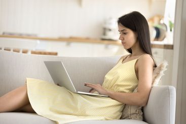 Concentrated young lady working on notebook sitting on...