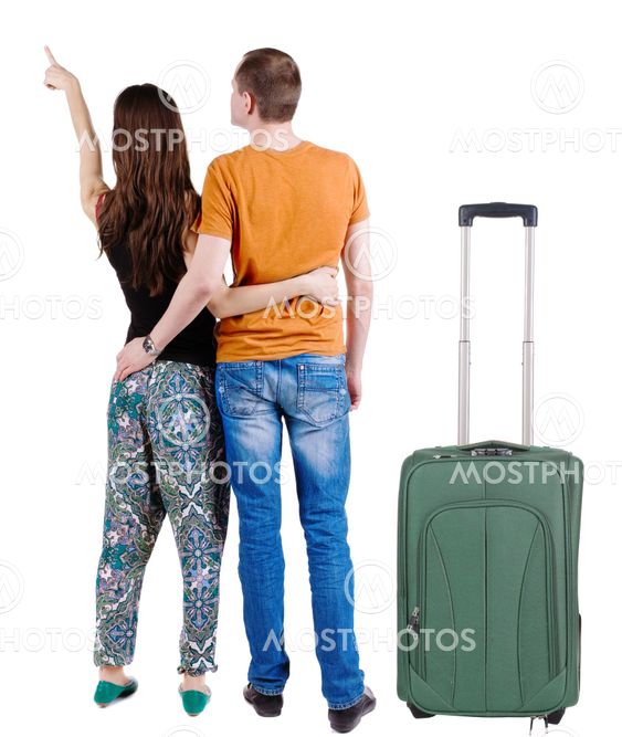 young couple traveling with suitcas and pointing at wal...