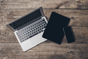 Multiple digital devices arranged on a wooden surface...