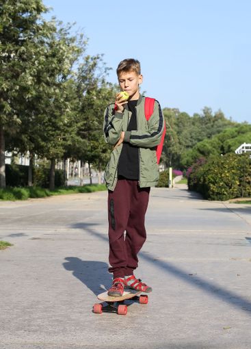 Handsome teenager standing with skateboard. Adolescent...