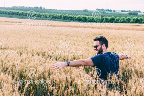 Young man resting in the wheat field at the sunset