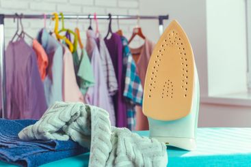Iron on ironing board on light home interior background