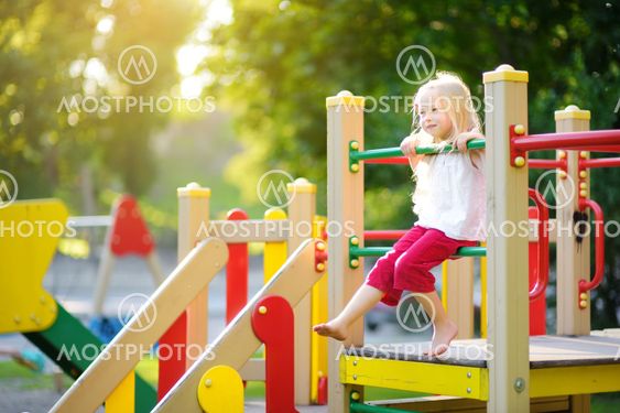Cute little girl having fun on a playground outdoors in...