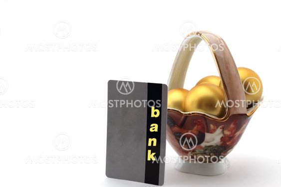 golden egg in porcelain chalice and bank card on white background