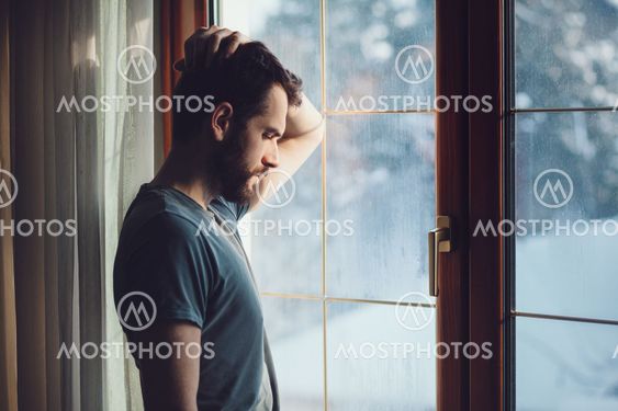 Young sad mad sitting by the window
