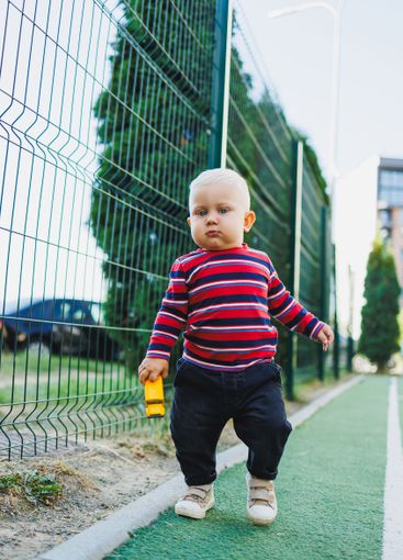 A fair-haired one-year-old boy in jeans and sneakers...