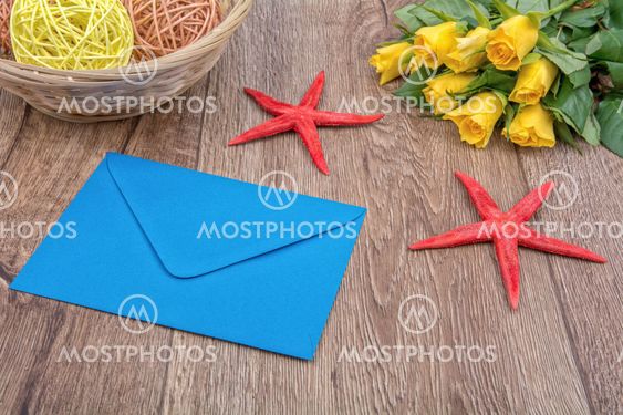 Envelope, starfishes and roses on a wooden background