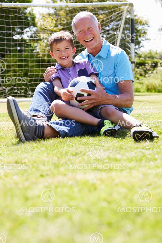 Grandfather And Grandson Playing Football In Garden