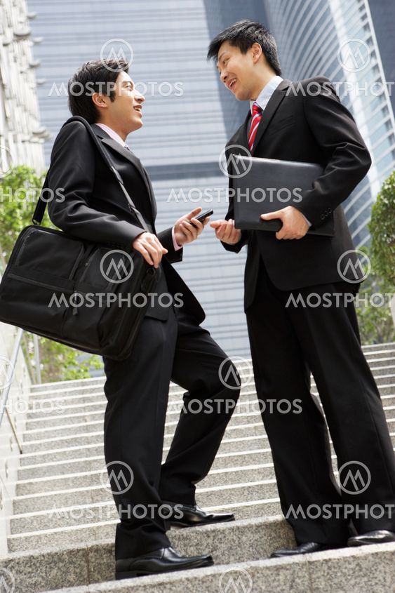 Two Chinese Businessmen Having Discussion Standing Outside Office
