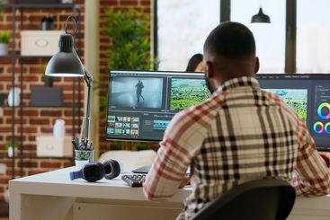 Male video editor works from modern home office in the...