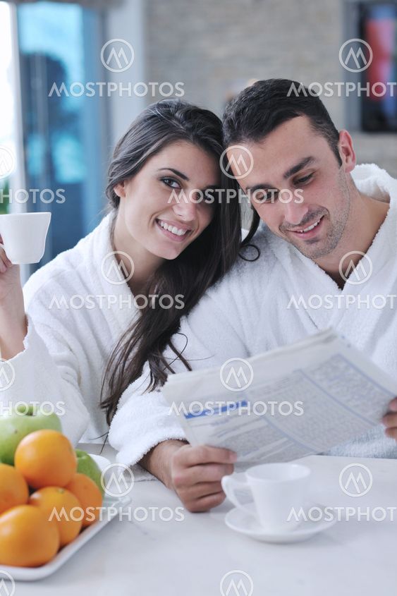 Happy couple reading the newspaper in the kitchen at breakfast