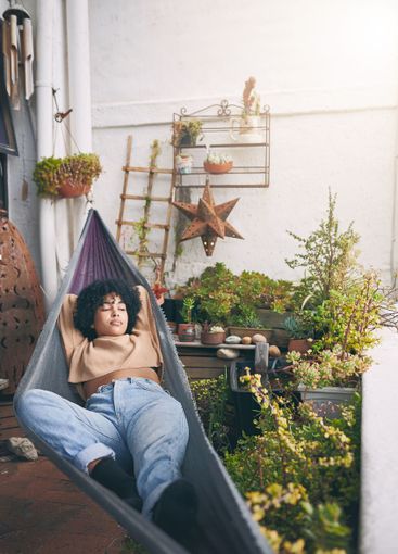Woman, relax and lying with hammock in garden for...