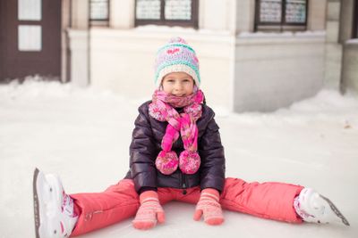 Little adorable girl sitting on ice with skates after the fall