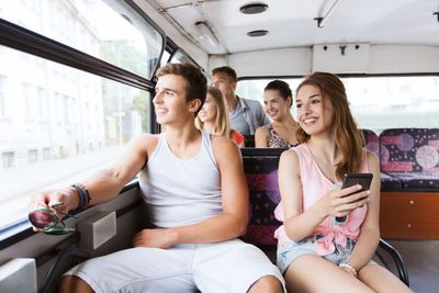 happy teenage friends traveling by bus