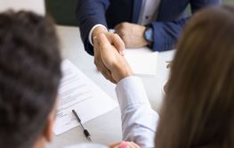 Above close up view of people shaking hands across table