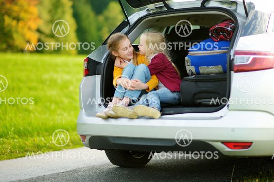Two adorable little girls sitting in a car before going...