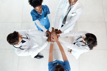 Doctor, meeting and hands together with unity above at...