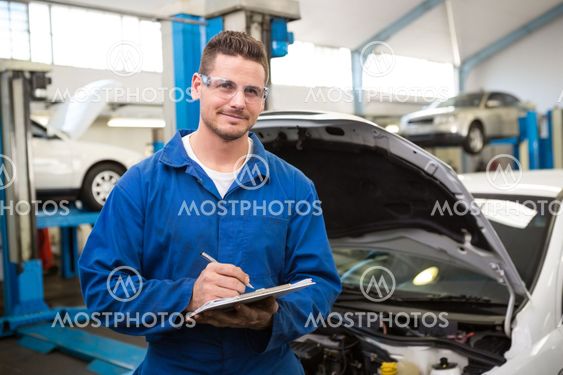 Smiling mechanic writing on clipboard