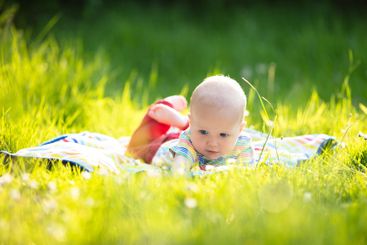 Baby boy with apple on family garden picnic