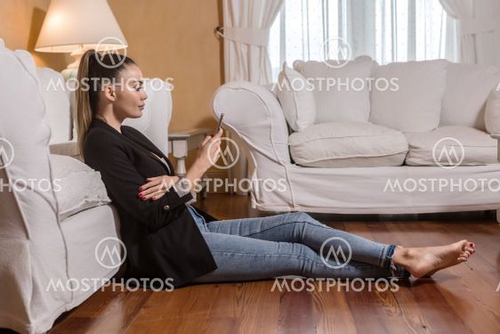 Barefoot businesswoman using smartphone on floor