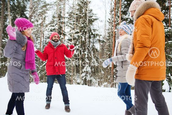 happy friends playing snowball in winter forest