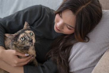 A woman lying on a couch, lovingly cuddling with her...
