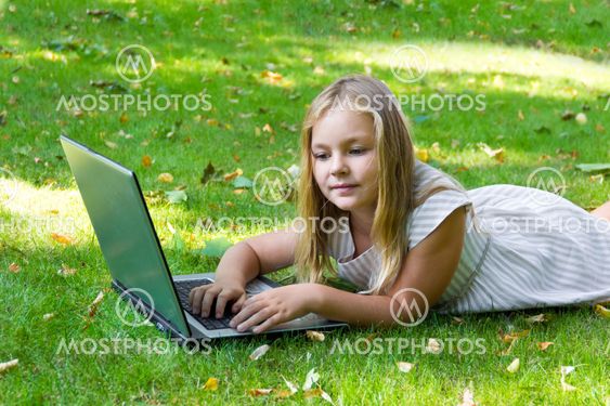 Cute girl with laptop on green grass