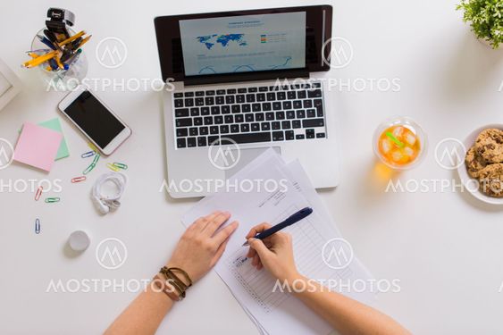hands with papers and laptop at office table