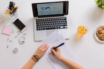 hands with papers and laptop at office table