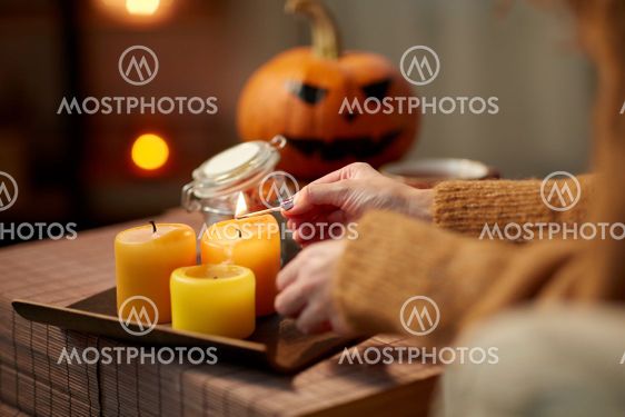 hand with match lighting candle on halloween