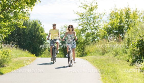happy young couple riding bicycles in summer