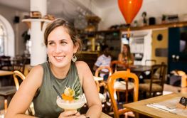 Portrait of young woman with colorful cocktail in restaurant