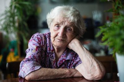 Portrait of an elderly woman sitting in a room at the...