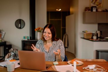 Smiling female freelancer talking on video call through...